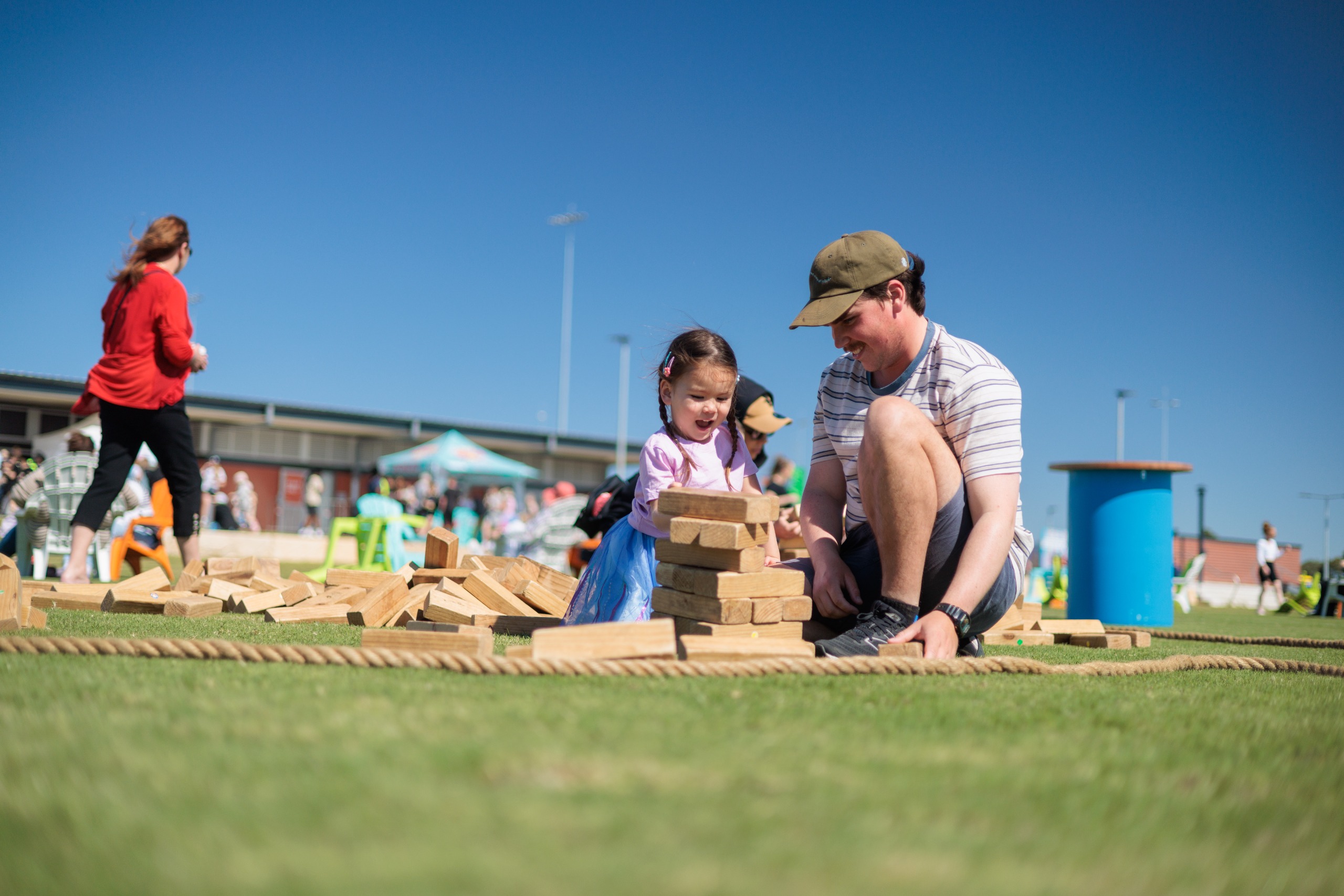 A young daughter and father playing on the grass