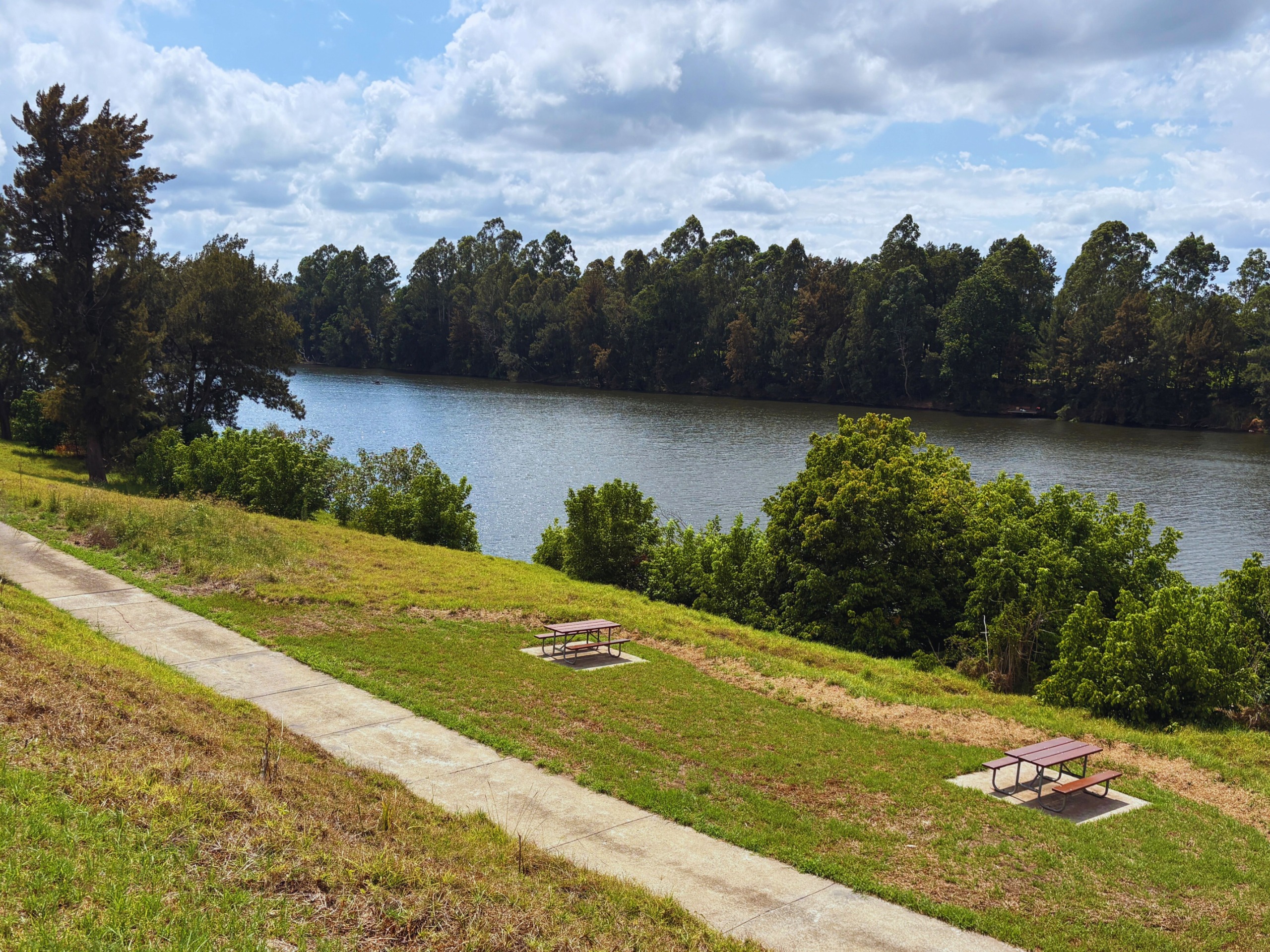 An image of a pathway and picnic tables with the Nepean River in the background.