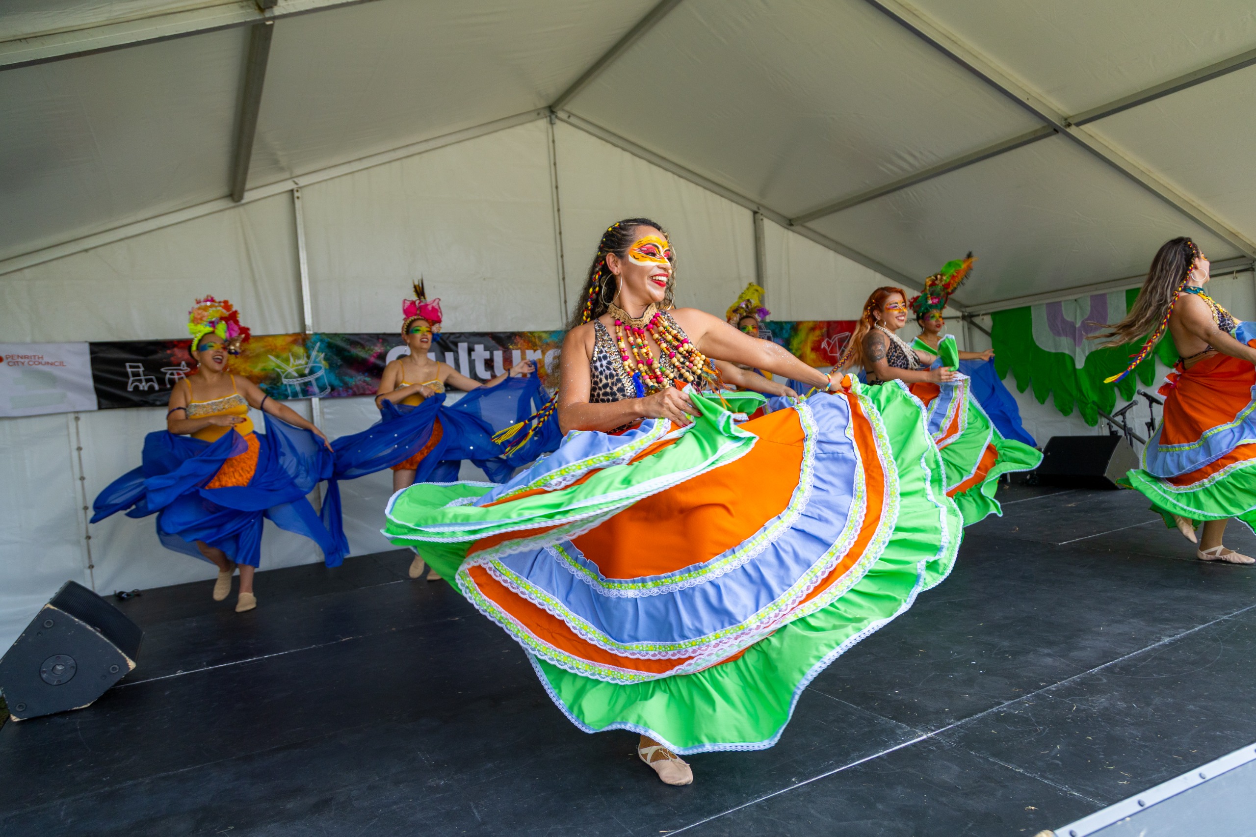 An image of dancers on stage wearing colourful costumes