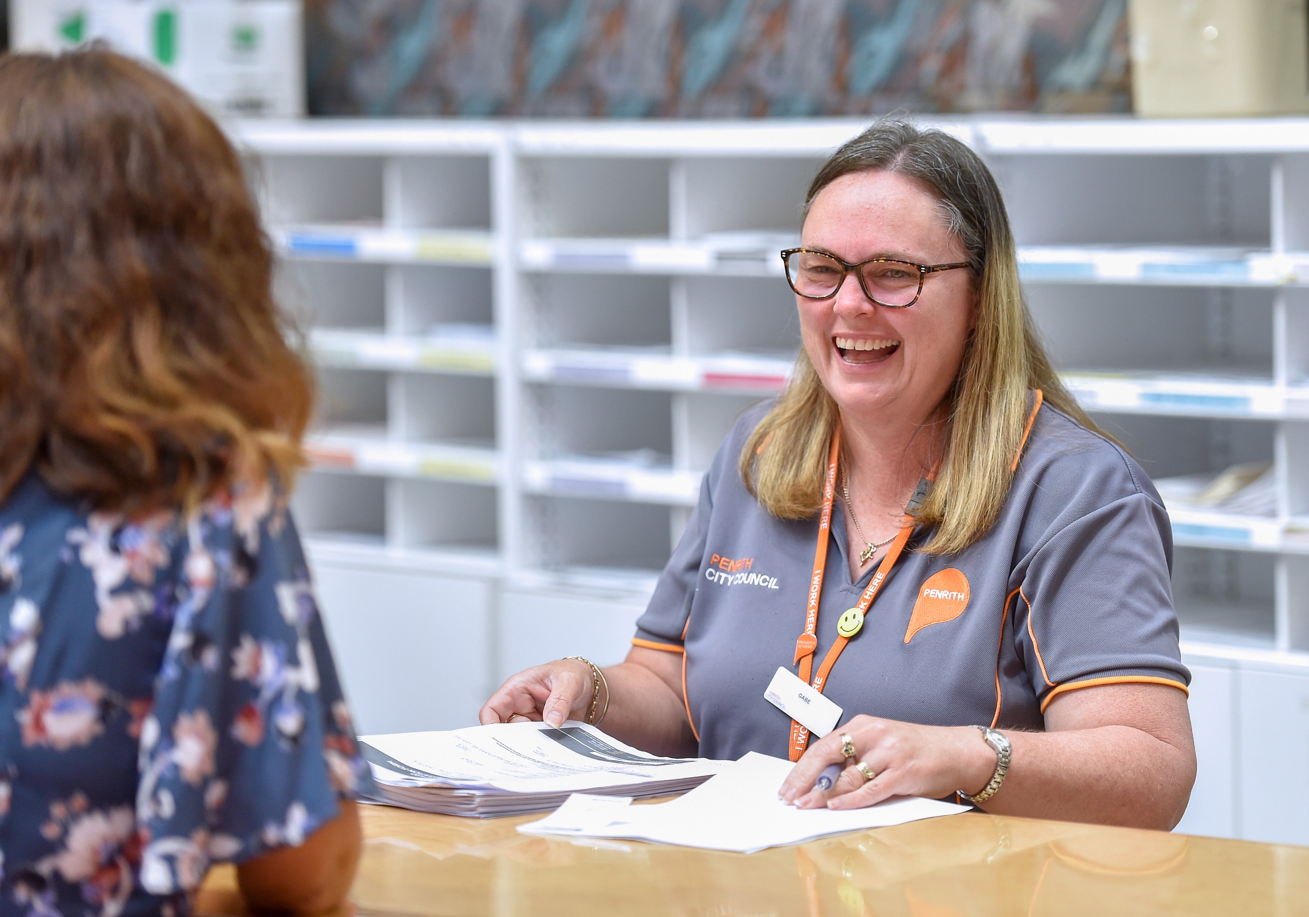 A woman serving a customer at a desk.