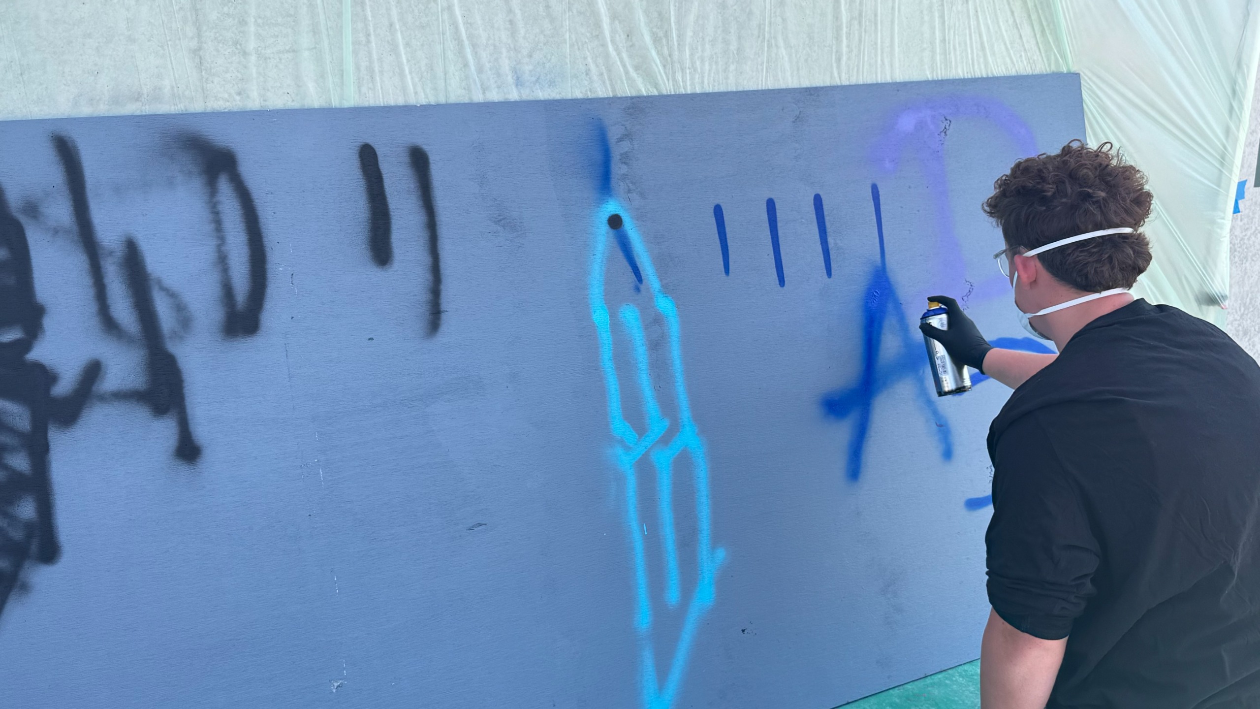An image of a young boy spray painting a mural