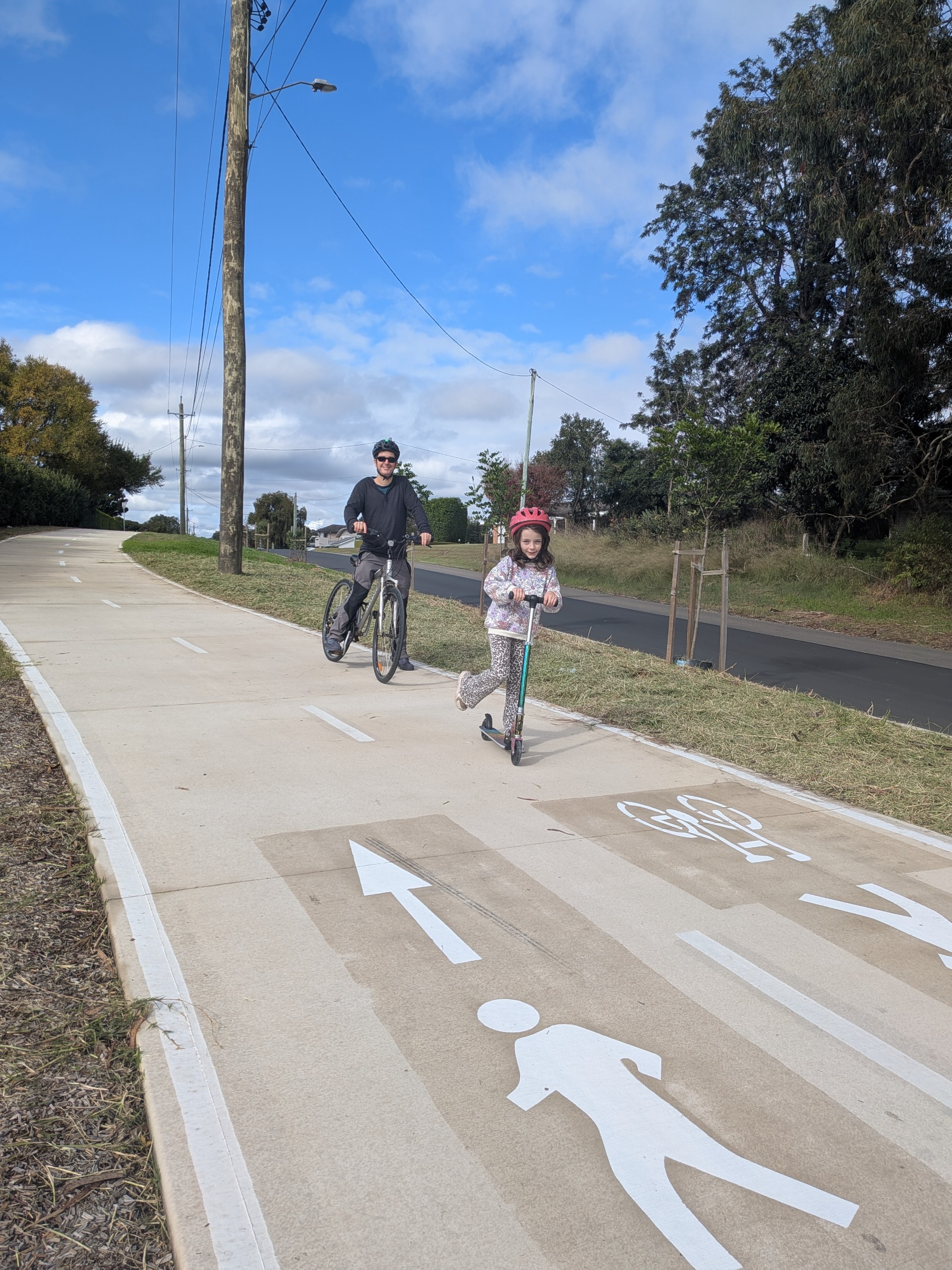 Child on scooter and man on bike riding down the Factory Road sharedpath